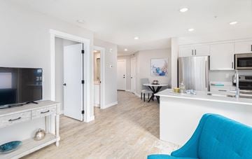 Calgary apartment for rent - A blue chair is in the foreground of a white kitchen and living room.