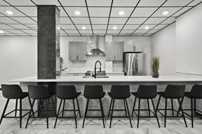 Calgary apartment for rent - A modern kitchen with a white countertop and black barstools.