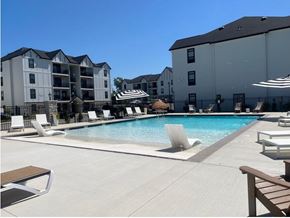 St. Peters apartment for rent - A swimming pool surrounded by lounge chairs and umbrellas in front of apartment buildings.
