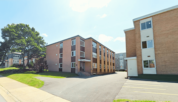 Halifax apartment for rent - A large brick building with a parking lot in front.
