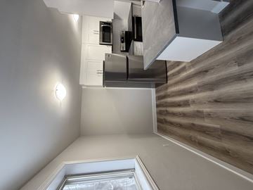 London apartment for rent - A modern kitchen with a stainless steel refrigerator and wooden wall paneling.