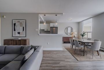 London apartment for rent - A modern living room with a grey sofa and a dining table set up.