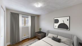 Moncton apartment for rent - A modern bedroom with a grey bed, a small table with a plant, and a painting on the wall.