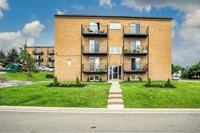 Moncton apartment for rent - A brick building with a green lawn in front.