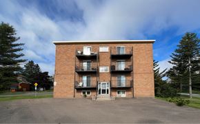 Moncton apartment for rent - A large red brick building with a balcony on the second floor.