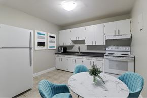 Moncton apartment for rent - A kitchen with a white fridge, white cabinets, a white countertop, and a white island with a marble top.
