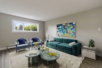 Moncton apartment for rent - A living room with a green couch, two blue chairs, and a painting on the wall.