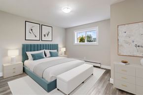 Moncton apartment for rent - A bedroom with a large bed and a window showing trees outside.