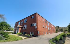 Moncton apartment for rent - A red brick building with a clear blue sky in the background.