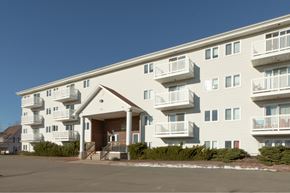Moncton apartment for rent - A large white apartment building with balconies and a covered entrance.