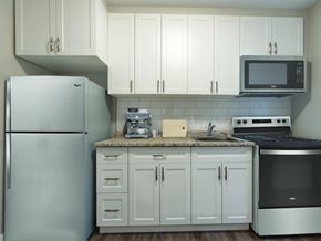 London apartment for rent - A kitchen with a refrigerator, microwave, oven, and cabinets.