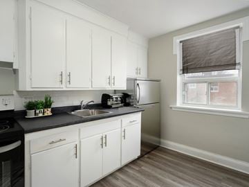Kitchener apartment for rent - A kitchen with white cabinets and a black countertop.