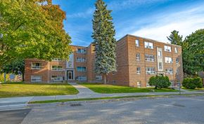 Kitchener apartment for rent - A large brick building with a tree in front of it.