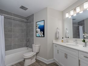 London apartment for rent - A bathroom with a white toilet, a white sink, and a painting of a beach scene on the wall.
