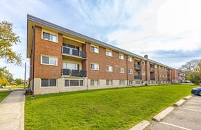 Kitchener apartment for rent - A red brick apartment building with a green lawn in front.