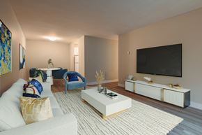 Bedford apartment for rent - A living room with a white couch, a blue chair, a white coffee table, and a flat screen TV mounted on the wall.