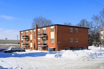 Kitchener apartment for rent - A red brick apartment building with snow on the ground and cars parked in front.