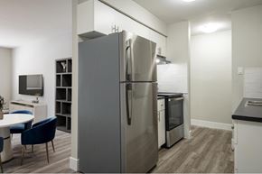 Halifax apartment for rent - A modern kitchen with a large refrigerator and a dining table with chairs.