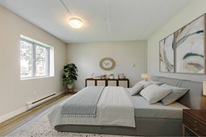 Thorold apartment for rent - A bedroom with a large bed and a clock on the wall.