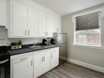 Hamilton apartment for rent - A kitchen with white cabinets and a black stove top.