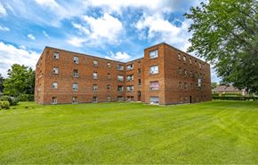 Hamilton apartment for rent - A large red brick building with a green lawn in front.