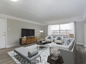 Hamilton apartment for rent - A living room with a grey couch, a grey ottoman, a black coffee table, a flat screen TV, and a white lamp.