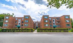 Hamilton apartment for rent - A large red brick building with green awnings and windows.