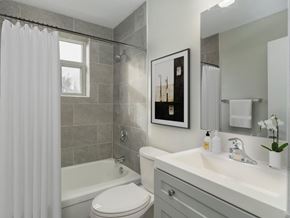 Hamilton apartment for rent - A bathroom with a white toilet, a white sink, and a shower with a white curtain.