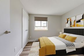 Waterloo apartment for rent - A bedroom with a bed, yellow pillows, and a window.