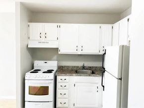 Moncton apartment for rent - A white kitchen with a stove, sink, and refrigerator.