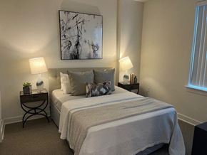 Suitland apartment for rent - A bedroom with a bed, two lamps, and a painting on the wall.