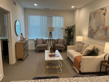 Suitland apartment for rent - A living room with a white couch, a coffee table, and a large painting on the wall.