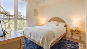 Los Angeles apartment for rent - A bedroom with a bed, nightstand, and a window overlooking a cityscape.