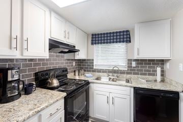 Savannah apartment for rent - A kitchen with white cabinets and a black stove top.