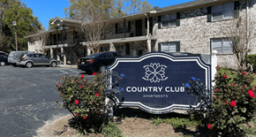 Summerville apartment for rent - A sign for Country Club Apartments is in front of a building.