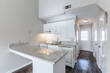 Gainesville apartment for rent - A kitchen with white cabinets and a granite countertop.