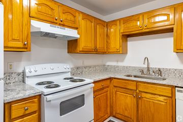 Gainseville apartment for rent - A kitchen with wooden cabinets and a white stove top oven.