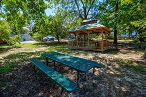 Evansville apartment for rent - A picnic table and bench are set up in a park with a gazebo in the background.