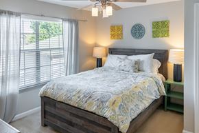 Auburn apartment for rent - A bedroom with a bed, a ceiling fan, and a window with curtains.