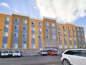 Rapid City apartment for rent - A large multi-story building with a parking lot in front.