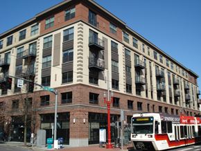 Portland apartment for rent - A red and white train is on the tracks in front of a building.