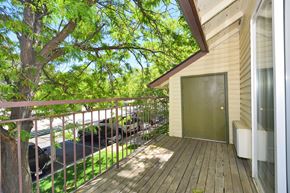 Twin Falls apartment for rent - A balcony with a green door and a tree in front of a house.