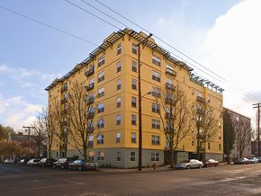 Portland apartment for rent - A yellow building with a green base and a parking lot in front.