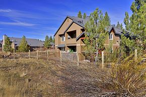 Truckee apartment for rent - A house with a brown roof and a grey garage door is surrounded by a fence and trees.