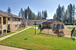 Grass Valley apartment for rent - A playground with a swing set and a fence is in the foreground of a residential area with houses and trees in the background.