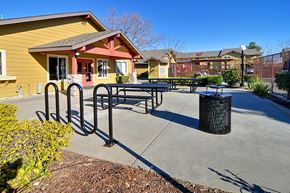 Oroville apartment for rent - A yellow building with a red door and a black trash can in front of it.