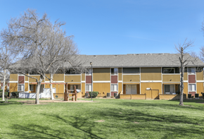 Perris apartment for rent - A building with a brown and tan exterior is surrounded by a green lawn.