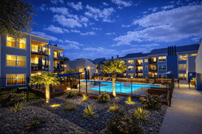 Euless apartment for rent - A modern building with a pool in the courtyard at dusk. at Infinity on the Landing Apartments , Apartments, Euless, TX