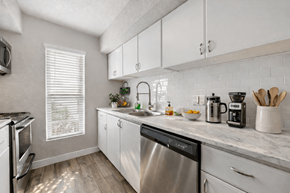 Euless apartment for rent - A kitchen with a stainless steel dishwasher and white cabinets. at Infinity on the Landing Apartments , Apartments, Euless, TX
