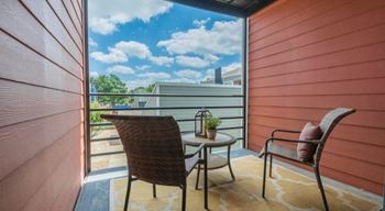 A balcony with a chair and table overlooking a building.